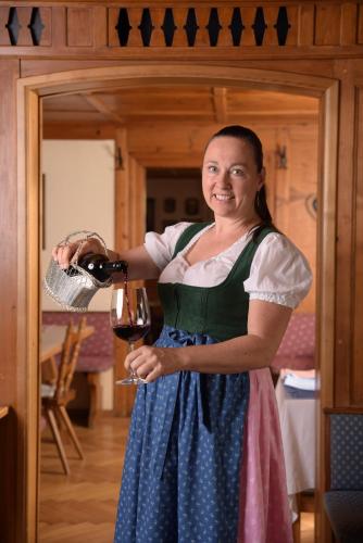 a woman is pouring a glass of wine at Gasthaus Kreuz in Schruns-Tschagguns