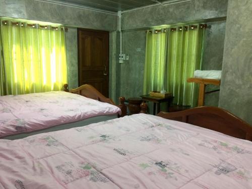 two beds in a room with green curtains at เฮือนฮอมคำโฮมสเตย์(Huanhomkham homestay) in Chiang Mai