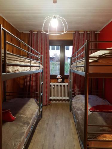 ein Zimmer mit zwei Etagenbetten und einem Fenster in der Unterkunft La Pinéguette maison 12 personnes spa 6 pers décoration chalet sauna 4 pers in La Bresse