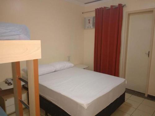a small bedroom with a bed and a red curtain at Di Roma Rio Quente in Rio Quente