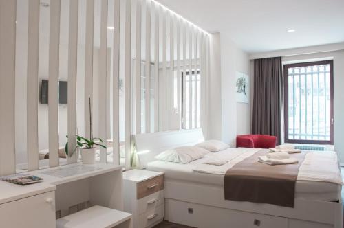 a white bedroom with a bed and a desk at B&B Schlosser in Zagreb