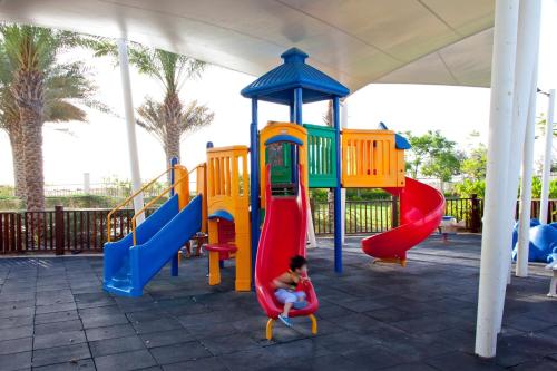 a boy sitting on a slide at a playground at Park Inn by Radisson Abu Dhabi Yas Island in Abu Dhabi