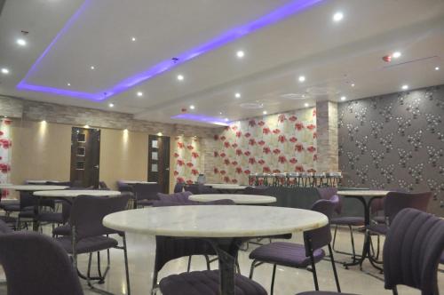 a restaurant with tables and chairs and a wall with flowers at Hotel Eastern Plaza in Kolkata
