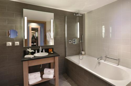 a bathroom with a tub and a sink and a tub and a mirror at La Mainaz Hôtel Restaurant Genève - Gex - Mijoux in Gex