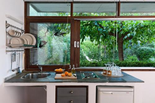 a kitchen with a sink and a large window at Studios Kyparissi & Spa in Tiros