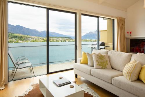 a living room with a couch and a view of the water at Villa Del Lago in Queenstown
