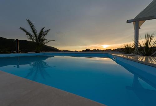 a swimming pool with a sunset in the background at Apartments Holidays Roko in Grebaštica