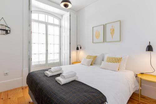 una camera bianca con un grande letto con asciugamani di Douro Virtudes Apartments Historical Center a Porto