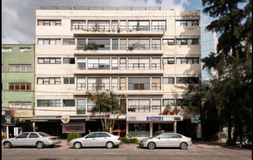 a large white building with cars parked in front of it at Pennsylvania WTC High End 1parking/2BR/2BA in Mexico City