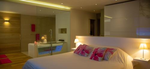 1 dormitorio con 1 cama blanca y 2 almohadas rosas en Villa AKA walking acces to beach, en Saint Barthelemy