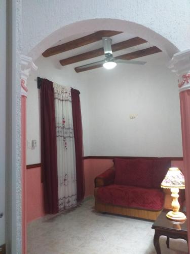 a living room with a red couch and a ceiling fan at Casa Palagui Colonial in Valladolid