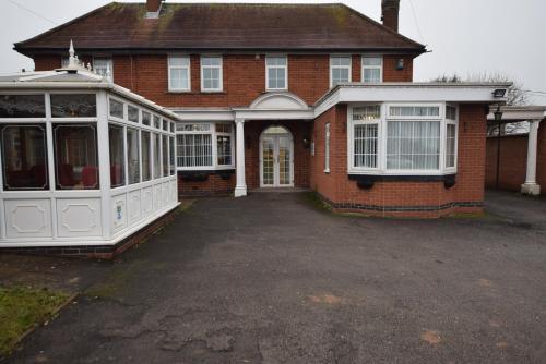 a red brick house with a conservatory and a driveway at The Watling Inn in Nuneaton