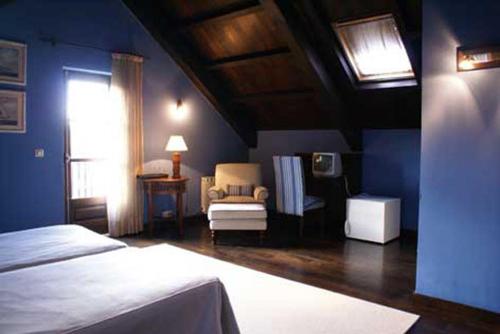 1 dormitorio azul con 1 cama y 1 silla en Hostal Meson Leira Antiga, en Cedeira