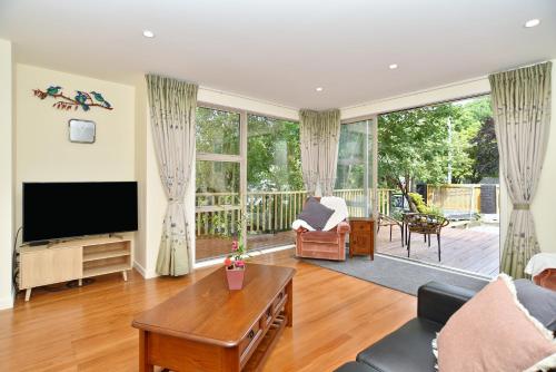 a living room with a flat screen tv and a table at Clyde 106 - Christchurch Holiday Homes in Christchurch