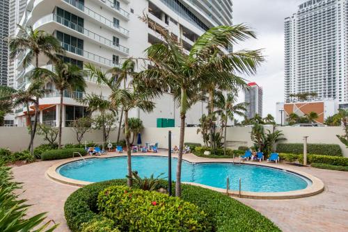 a swimming pool with palm trees and a building at Paradise on Hollywood Beach 2 bed 2 bath in Hollywood