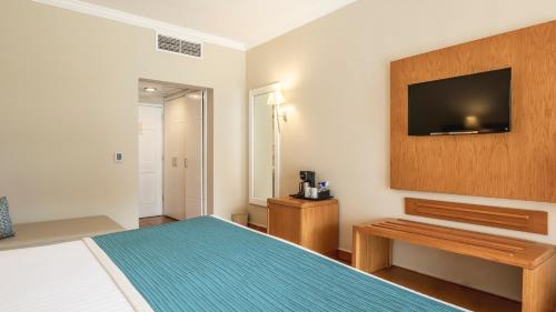 a hotel room with a bed and a television at Be Live Collection Canoa - All Inclusive in Bayahibe