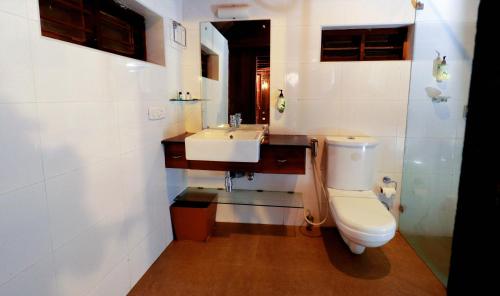 y baño con aseo y lavamanos. en Triveny River Palace en Alleppey