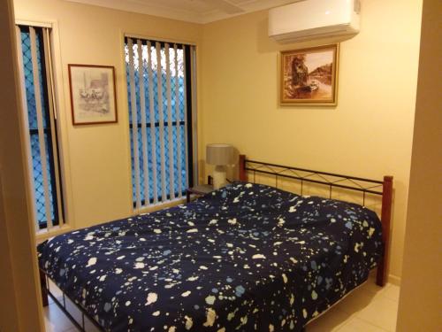 a bedroom with a bed with a blue blanket with flowers at Banksia and Acacia Apartments in Maryborough