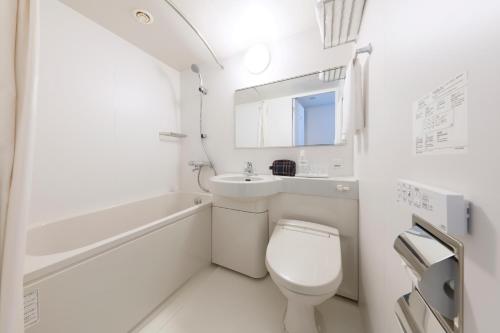 a white bathroom with a toilet and a sink at Hotel It Osaka Shinmachi in Osaka