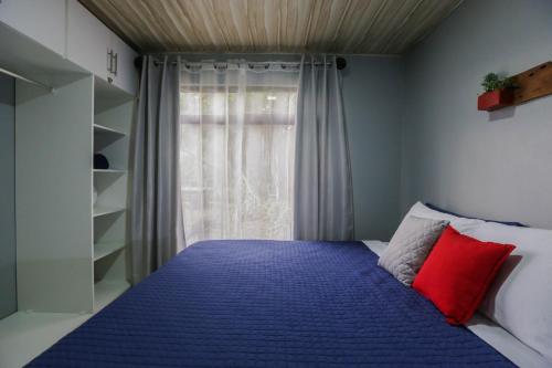 a bedroom with a blue bed with a window at Casa Suculenta ,Monteverde con Jacuzzi Privado y Lavandería in Monteverde Costa Rica