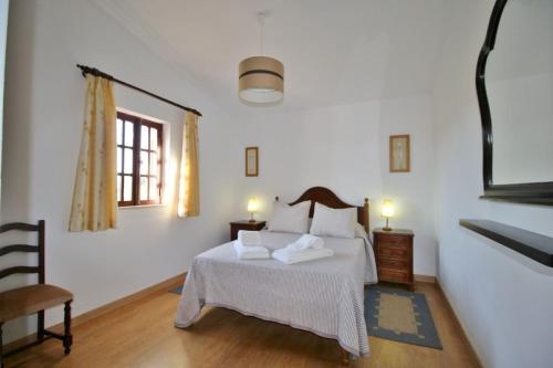 a white bedroom with a bed and two lamps at Horta Nova in Lagos