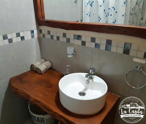 a bathroom with a white sink on a wooden counter at Cabaña de Montaña, La Casita Mina Clavero CBA in Mina Clavero