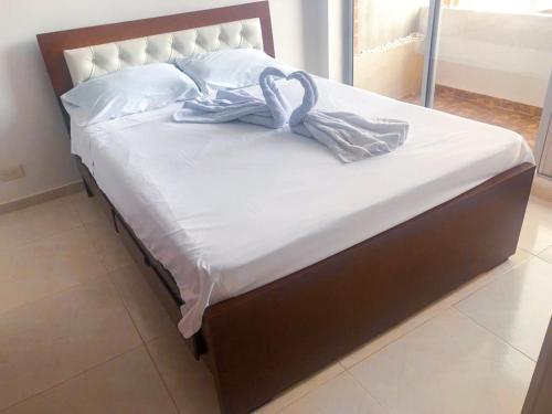 a bed with white sheets and towels on it at Sensacional Apartamento Reserva Peñon Girardot in Girardot
