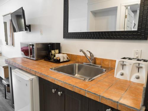 eine Küchentheke mit einer Spüle und einer Mikrowelle in der Unterkunft Motel Classique in Joliette