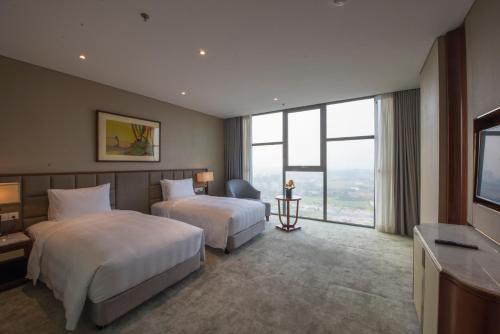 a hotel room with two beds and a flat screen tv at Wyndham Garden Hanoi in Hanoi