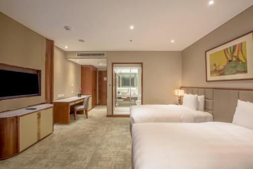 a hotel room with two beds and a flat screen tv at Wyndham Garden Hanoi in Hanoi