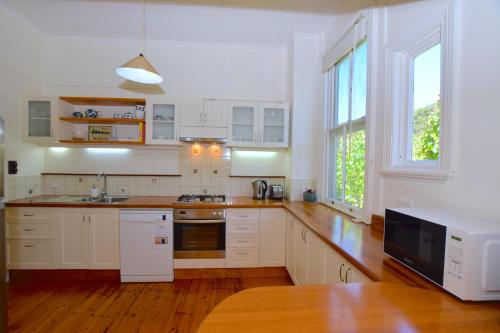 a kitchen with white cabinets and a large window at Mintie Cottage on Leura Mall in Leura