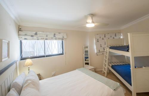a bedroom with two bunk beds and a window at Plett Beachfront Accommodation in Plettenberg Bay