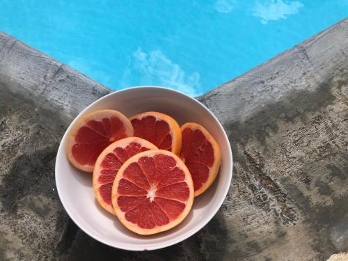 a bowl of grapefruit on a table next to a pool at OUR ISLAND HOME 5 MINS WALK TO BEACH in Flic-en-Flac
