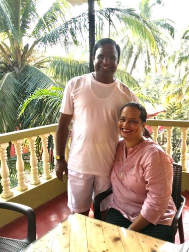 a man and a woman sitting at a table on a balcony at LaligurasVilla Beachside Escape - 100m to Beach in Candolim