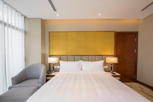 a bedroom with a large white bed and two chairs at Wyndham Garden Hanoi in Hanoi