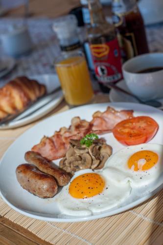 a plate of breakfast food with eggs sausage and mushrooms at Plett Beachfront Accommodation in Plettenberg Bay