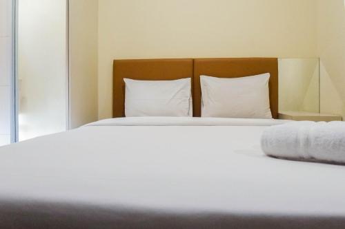 a large white bed with white sheets and pillows at Elegant Studio Apartment at Tamansari Papilio By Travelio in Surabaya