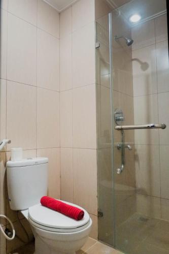 a bathroom with a toilet and a glass shower at Elegant Studio Apartment at Tamansari Papilio By Travelio in Surabaya