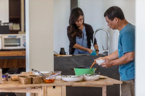 un homme et une femme dans la cuisine préparant la nourriture dans l'établissement Le Retour Du Printemps Villa, à Renai