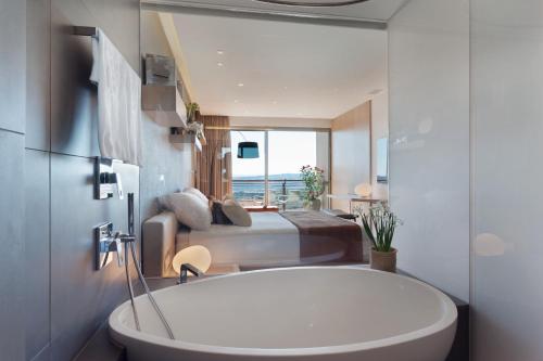 a bathroom with a tub and a bedroom with a bed at Cramim by Isrotel Exclusive in Qiryat ‘Anavim