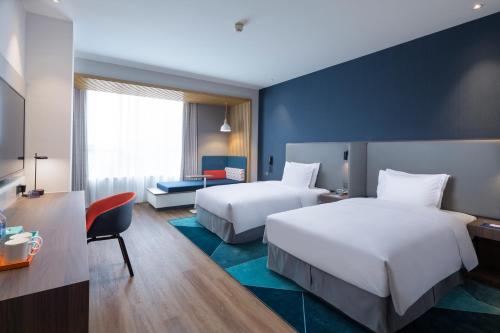 a hotel room with two beds and a desk at Holiday Inn Express Shanghai Kangqiao by IHG in Shanghai