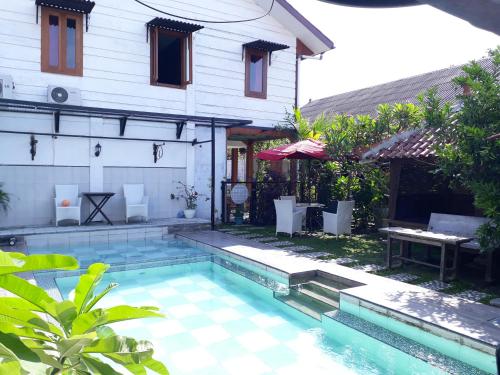 a house with a swimming pool in front of a house at Arjuna Garden Homestay in Yogyakarta