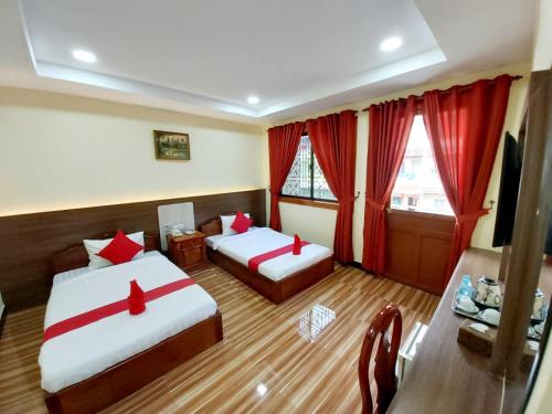 a hotel room with two beds and red curtains at Capitol One in Phnom Penh