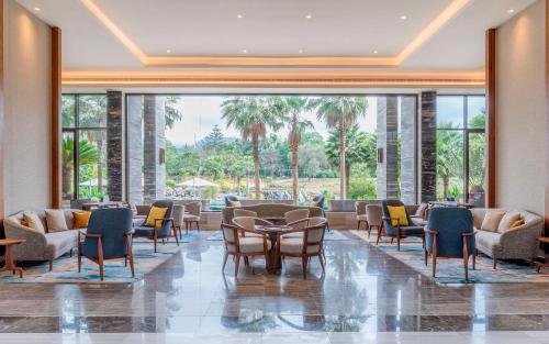 a lobby with chairs and tables and a large window at Gran Melia Arusha in Arusha