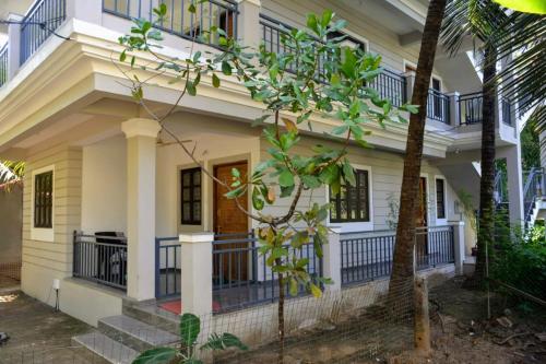 a white house with balconies and a tree at DSK Studio Apartment, Siolim, Goa. in Siolim