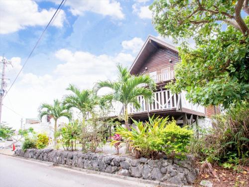 a house on the side of a street with trees at Kariyushi Condominium Resort Yuudekiya in Onna
