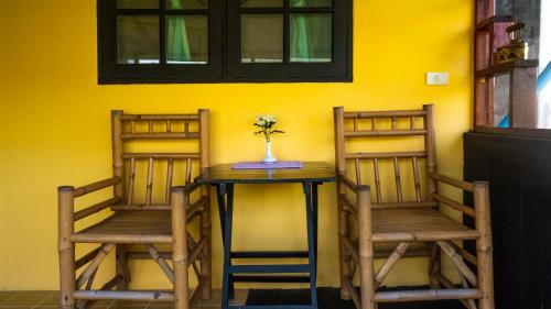 duas cadeiras e uma mesa num quarto com uma parede amarela em Sabina Guesthouse Kamala em Praia de Kamala