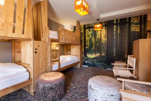 a room with wooden bunk beds and stools at Hotel Base Camp Lodge - Bourg Saint Maurice in Bourg-Saint-Maurice