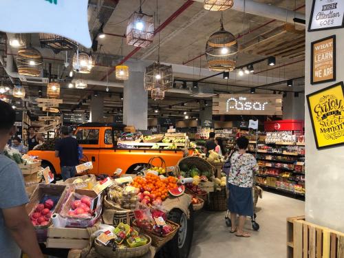 a market with people standing in a store with fruits and vegetables at Teega Residence @ Cosy Seafront Living in Nusajaya