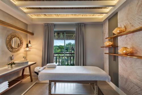 a bedroom with a bed and a sink and a window at Preskil Island Resort in Blue Bay